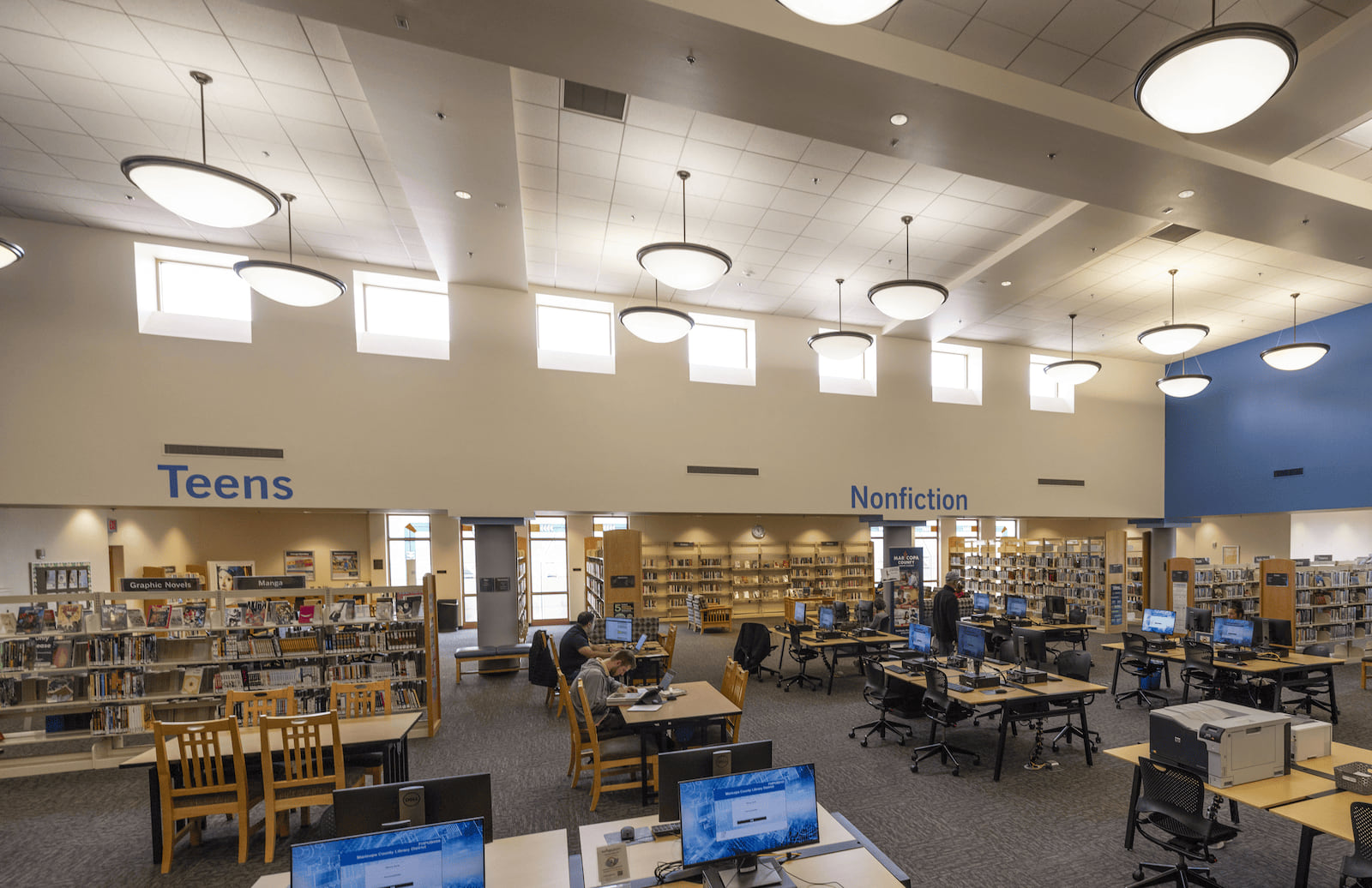 Photo of the computer area, tables, the teens section and Nonfiction section